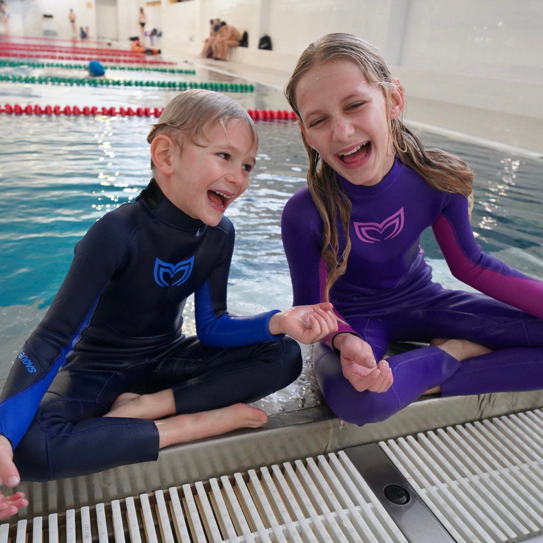 A child swimming with dolphins and wearing a kids wetsuit