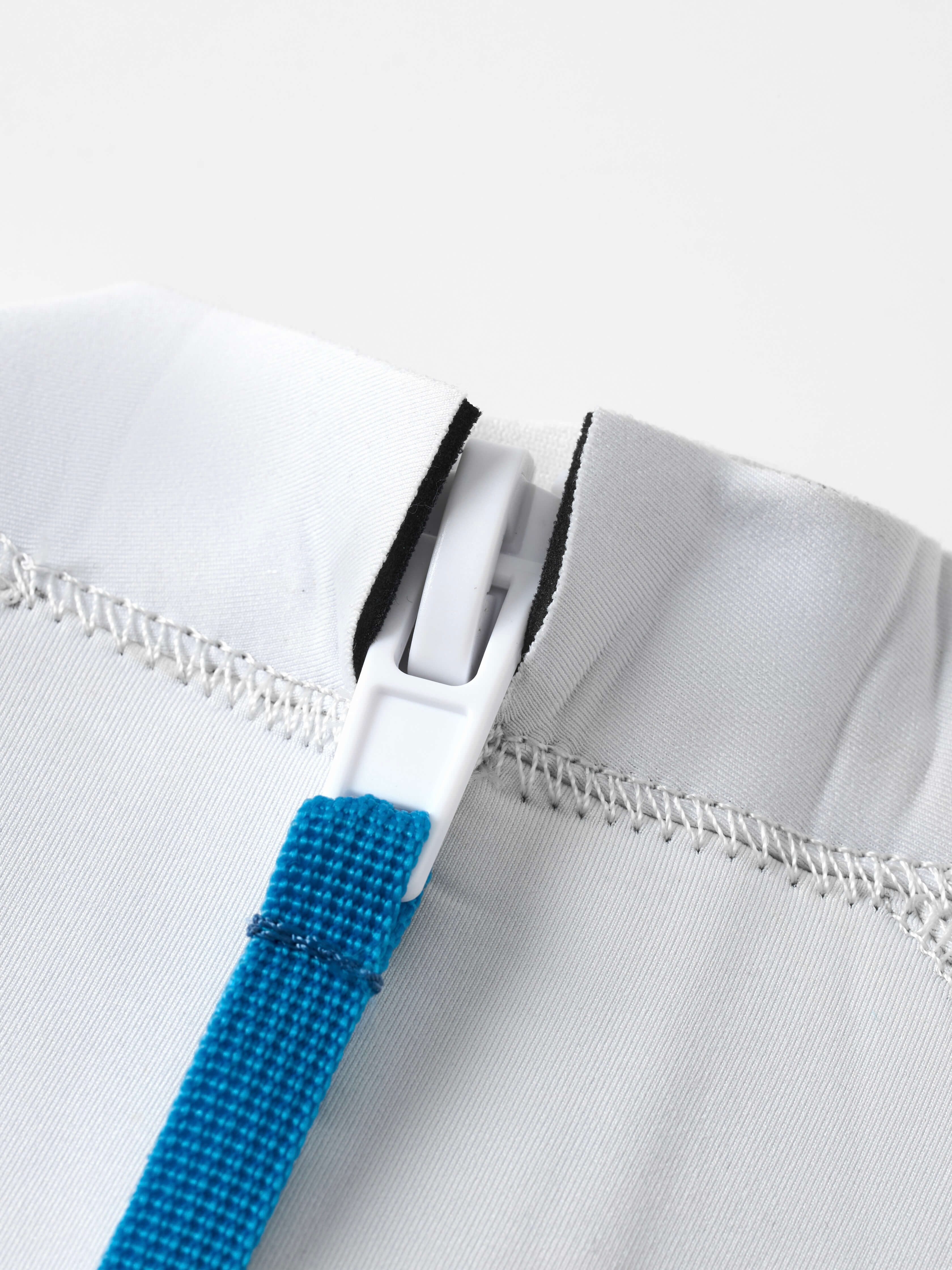 Yanita springsuit zipper close-up with blue strap and white buckle