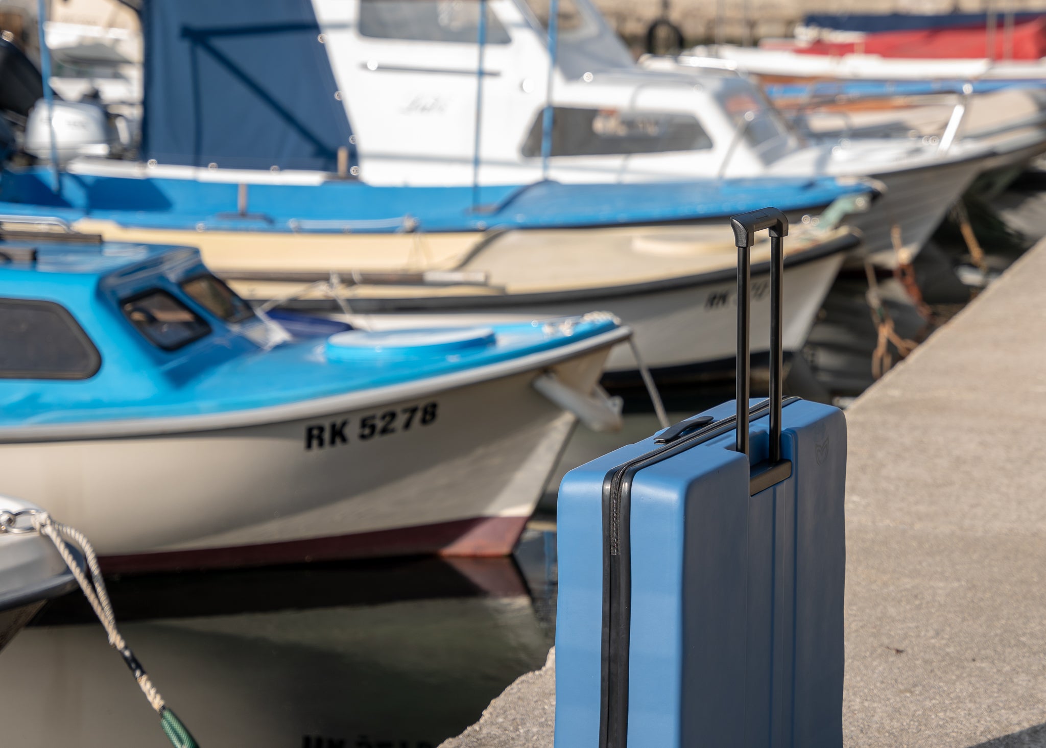 Blue Hard Case on a pier with boats in the background